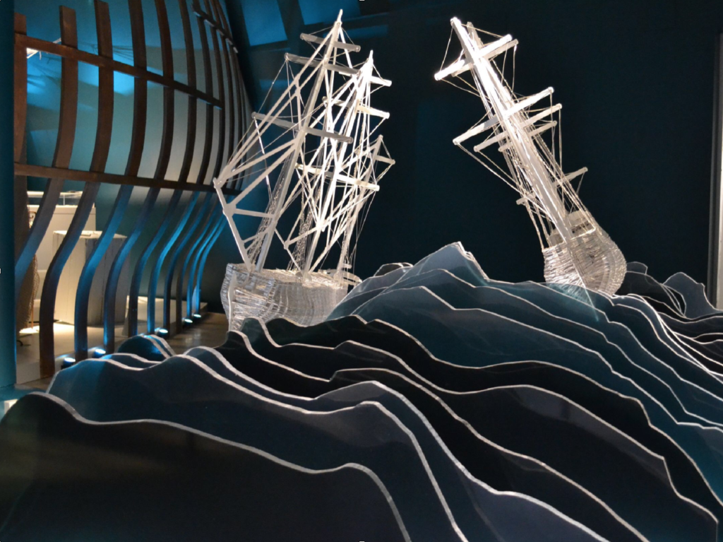 image of model ships made from transparent materials on wave like cut out shapes.